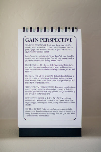 An image of the 52-Week Self-Improvement and Character Development Flip Book displaying the "Gain Perspective" page. The page features suggestions for activities to help clear the mind and find focus, such as journaling, prioritizing tasks, and seeking clarity from others.