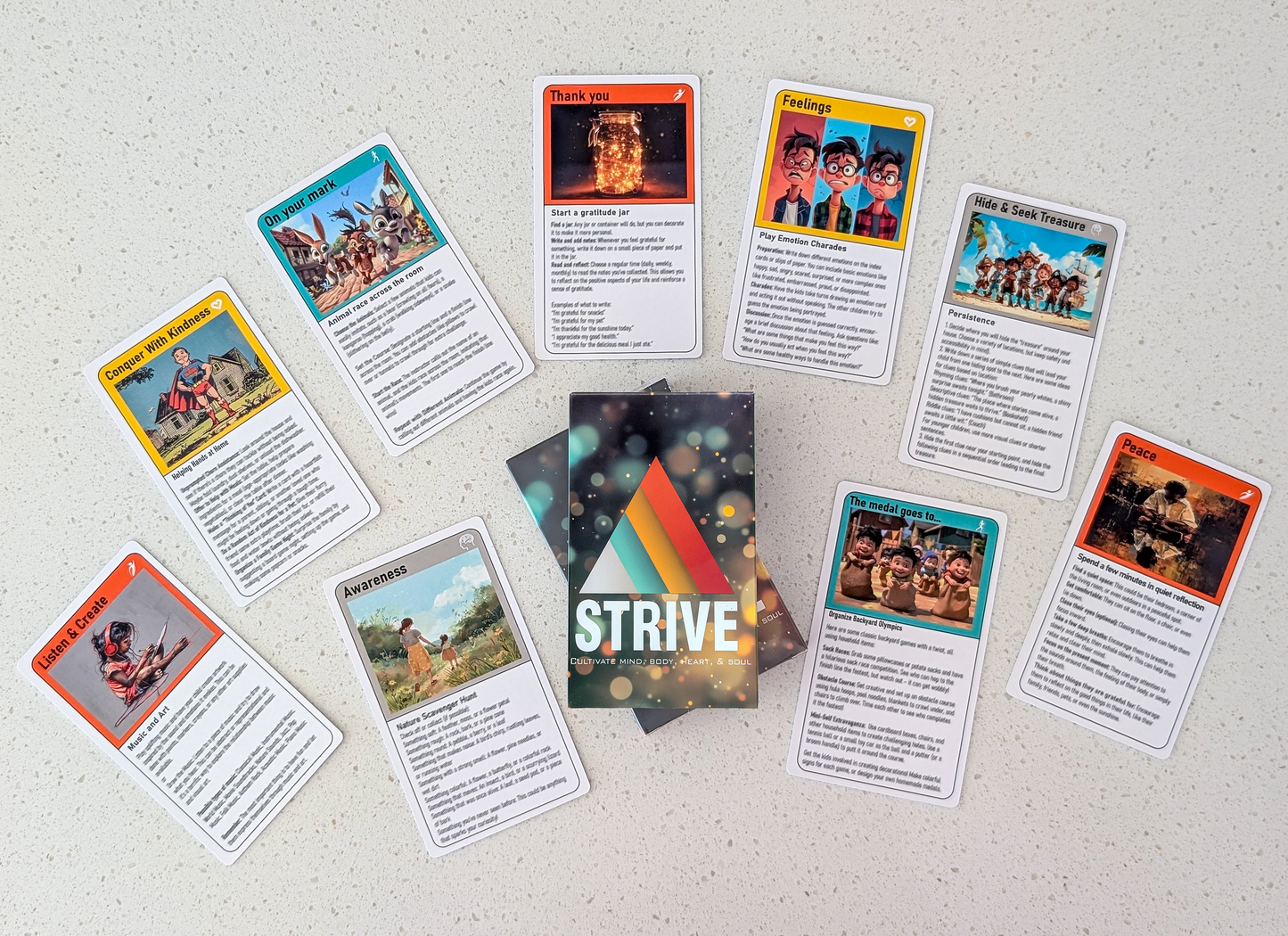 A flat lay of the activity cards for children.  Ten cards are fanned out around the deck's packaging, each featuring unique artwork and titles. Some examples include "Conquer With Kindness," "Listen & Create," and "Peace."